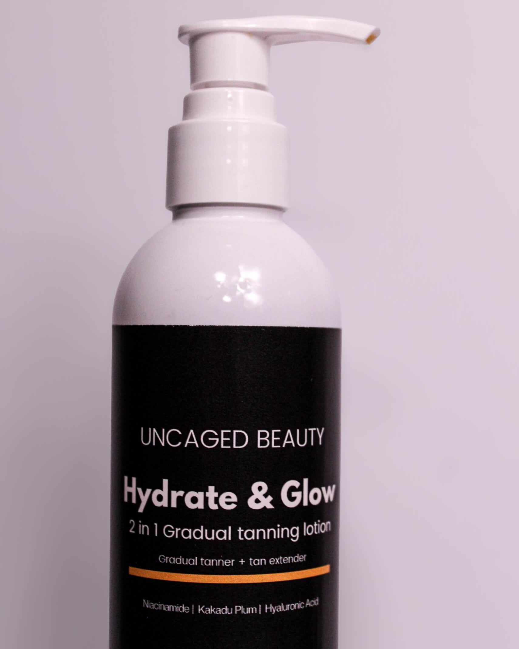 Bottle of 'Hydrate & Glow' tanning lotion by Uncaged Beauty on a gray background
